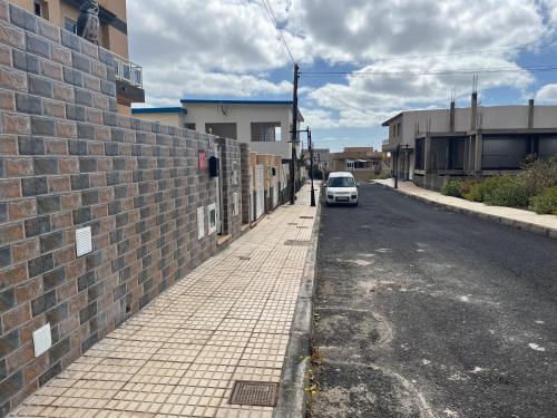 a white car parked on a street next to a brick wall at VV EL OASIS in Tamaduste