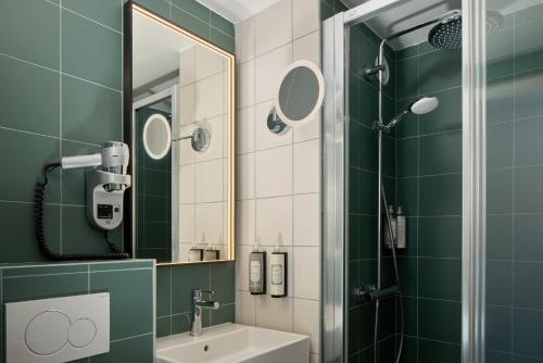 a green bathroom with a sink and a shower at Timhotel Nation in Paris
