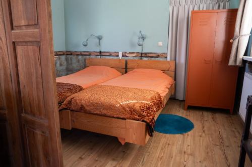 two twin beds in a small room with wooden floors at Het Zomerhuis in Egmond-Binnen
