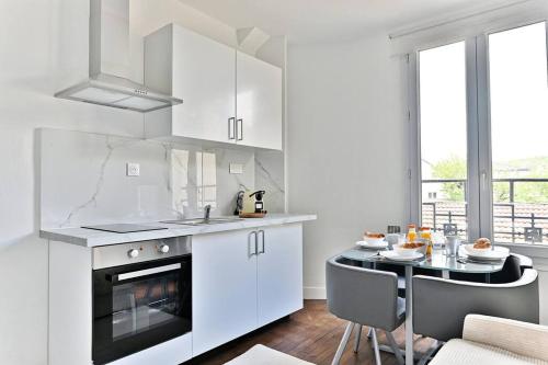 une cuisine avec des placards blancs et une table avec une salle à manger dans l'établissement Peaceful Apartment next to Paris - Gagny, à Gagny