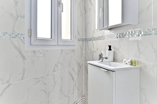 une salle de bain blanche avec un lavabo et un miroir dans l'établissement Peaceful Apartment next to Paris - Gagny, à Gagny
