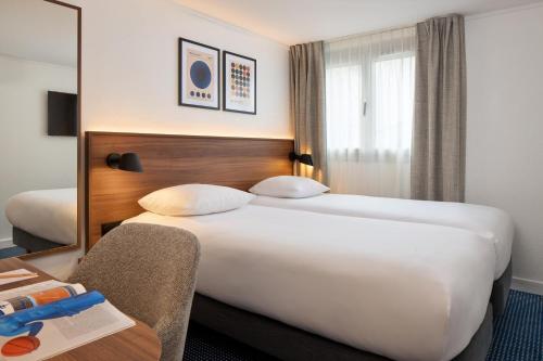 パリにあるティモテル ナシオンのベッド2台と鏡が備わるホテルルームです。
