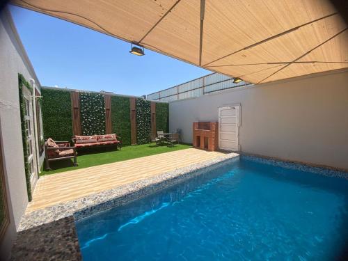 a house with a swimming pool and a patio at شاليهات الرويلي in Al Fayşalīyah