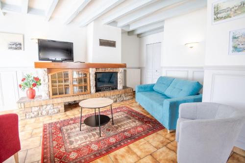 een woonkamer met een blauwe bank en een open haard bij L'Intriguante - Maison avec jardin pour 6pers. in Bléré