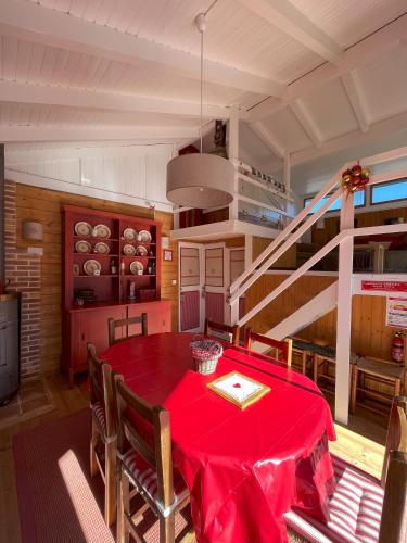 a dining room with a red table and a staircase at Chalet des Myrtilles - chalet cosy avec vue in Arette