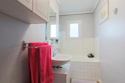 ein Bad mit einem Waschbecken und einem roten Handtuch in der Unterkunft Maison de vacances proche mer in Plouha