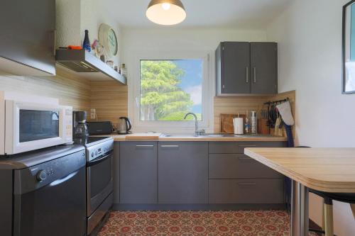 une cuisine avec un évier et un micro-ondes dans l'établissement Maison proche mer Plouha, à Plouha