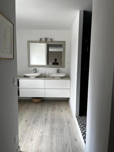 une salle de bain blanche avec deux lavabos et un miroir dans l'établissement La Casa Familia à Fontainebleau, à Grez-sur-Loing