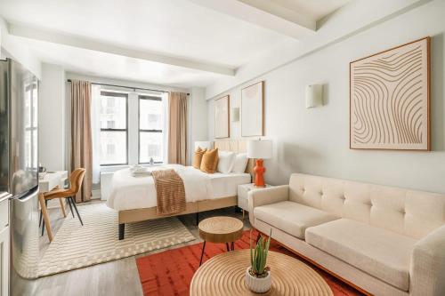 ein weißes Schlafzimmer mit einem Bett und einem Sofa in der Unterkunft 73-1104 New Studio UWS Doorman Gym in New York