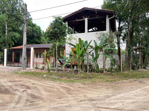 a white building with a porch next to a dirt road at Vila Guaraú in Peruíbe