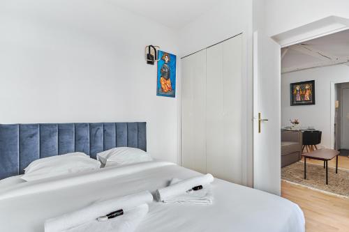 1 Schlafzimmer mit einem weißen Bett und einem blauen Kopfteil in der Unterkunft Charming 1 bedroom flat Coeur du Marais By Studio Prestige in Paris
