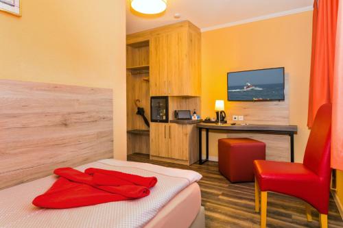 奥斯科瑟羅的住宿－Hotel & Restaurant Hanse Kogge，客房设有床、书桌和红色椅子。