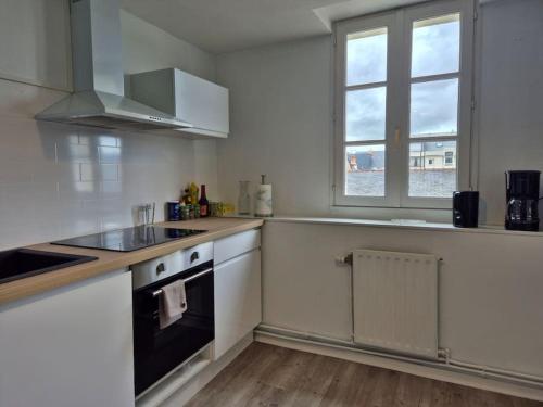 une cuisine blanche avec une cuisinière et une fenêtre dans l'établissement les carmes, à Angers