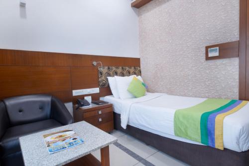 a hotel room with a bed and a chair at Treebo Ambassador in Ahmedabad