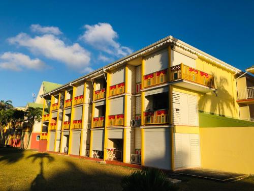 a yellow and white building with balconies on it at Studio Kawane Anse des rochers 303 RDC, côté mer in Saint-François