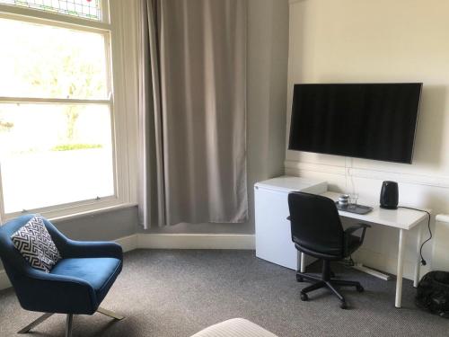 a room with a desk and a tv and two chairs at Green Lodge-Room-04 in Liverpool