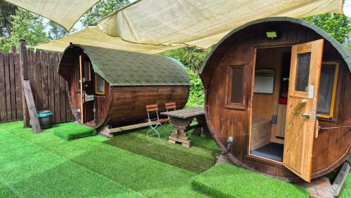um par de pequenas cabanas de madeira na relva em Mini Hotel Übernachten Im Gurkenfass em Lübbenau