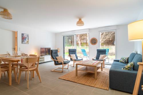 un salon avec un canapé, une table et des chaises dans l'établissement Trévarec au Cabellou - Appartement jardin sur la plage, à Concarneau