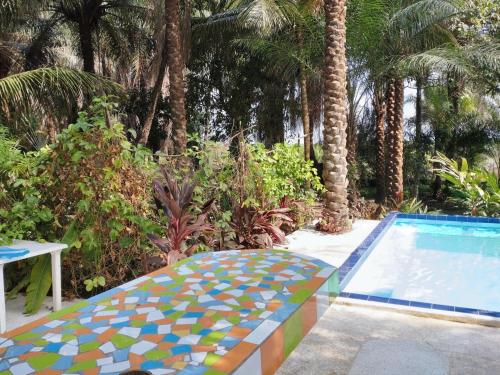 a swimming pool with a mosaic table and palm trees at 3 bedrooms house at Cap Skirring 800 m away from the beach with lake view private pool and enclosed garden in Cap Skirring