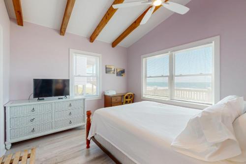 a bedroom with a bed and a flat screen tv at HB21 Austin Cottage in Holden Beach