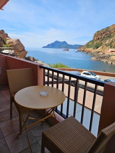 een tafel en stoelen op een balkon met uitzicht op het water bij Le monte rosso in Porto Ota