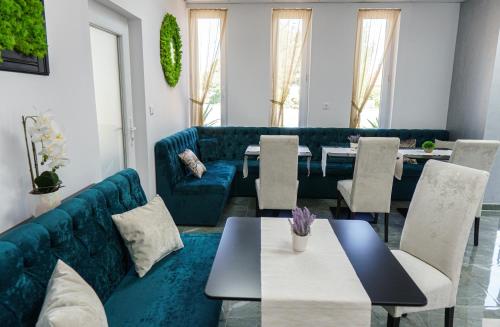 a living room with a blue couch and tables at Bécs Panzió Lenti in Lenti