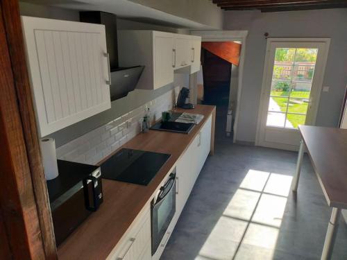 a kitchen with white cabinets and a sink at Longère 10 personnes in Vauchelles-lès-Quesnoy