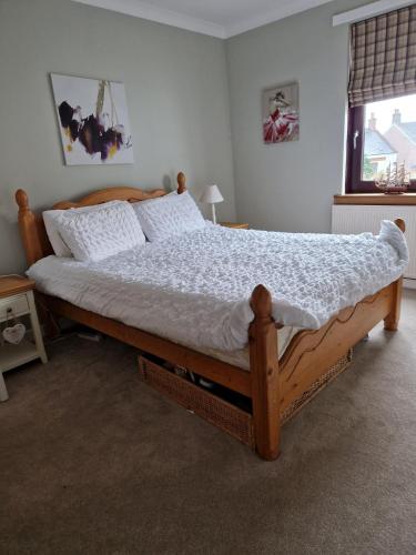 Un dormitorio con una gran cama de madera con sábanas blancas. en Troon Open golf - Private house with garden in central Prestwick en Prestwick