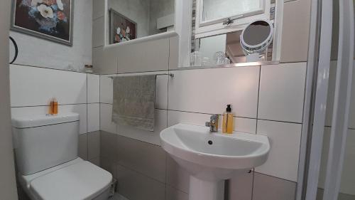 a white bathroom with a toilet and a sink at Vergenoegd Guesthouse in Panorama
