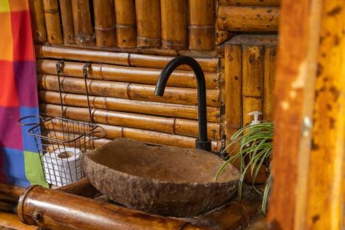 ein Steinwaschbecken mit einem Wasserhahn in einer Holzwand in der Unterkunft Cabaña Eco amigable en medio de la montaña. in Pastales