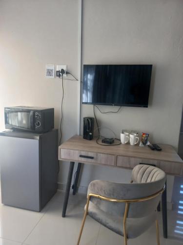 a desk with a television and a chair in a room at Achimer guesthouse in Kroonstad