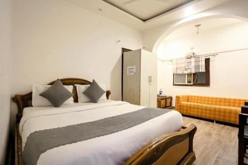 Hotel Shillo Nizamuddin في نيودلهي: غرفة نوم بسرير كبير وأريكة