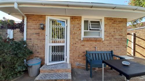 a brick house with a white door and a bench at Vergenoegd Guesthouse in Panorama