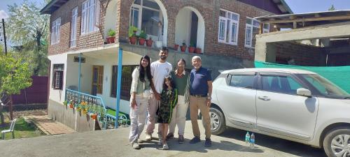 a family is standing in front of a house at Elizabeth paying guest house Tangmarg gulmarg in Gulmarg
