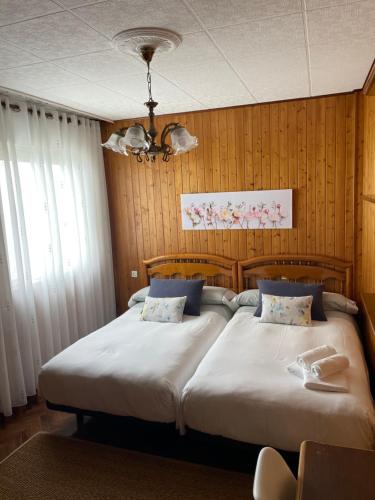two beds in a bedroom with wood paneling at Piso O Percebe in Muxia