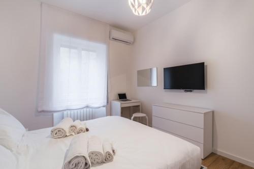 una camera da letto bianca con un letto e una TV a schermo piatto di THE FIFTH Properties a Roma