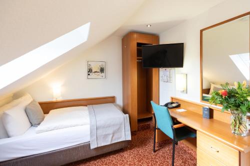 Habitación de hotel con cama, escritorio y TV. en Hotel Garden Bremen en Bremen