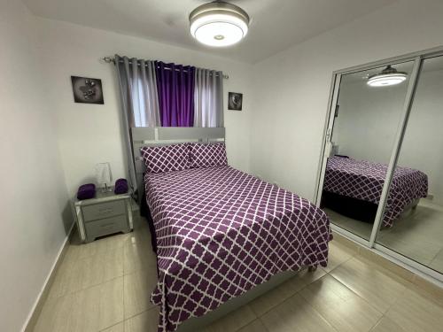 a bedroom with a bed with a purple comforter and a mirror at Joel Arturo Residences in Licey al Medio