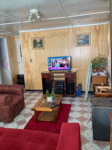 sala de estar con sofá y TV en Cabaña independiente, en Coyhaique