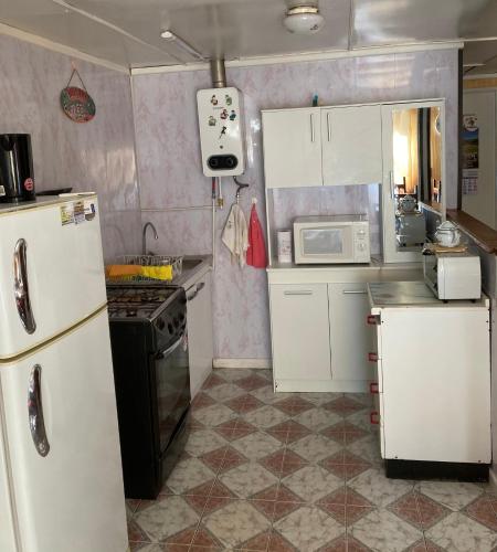 una pequeña cocina con armarios blancos y nevera. en Cabaña independiente, en Coyhaique