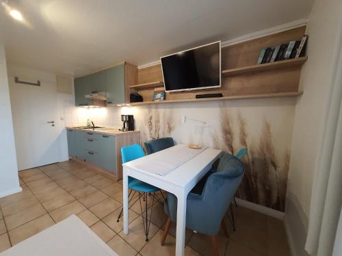 a small kitchen with a white table and blue chairs at Haus Achtern Diek in erster Reihe am Meer in Fehmarn