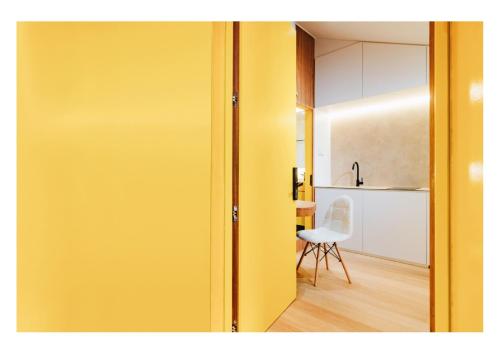 uma porta amarela que leva a uma cozinha com uma cadeira em Serenity Suite em Singapura