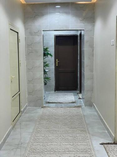 a hallway with a black door and a tile floor at شقة ريم الوجة in Al Wajh