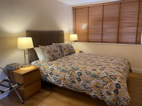 1 dormitorio con 1 cama, 2 lámparas y ventana en Clay Farm Guest House, en Bromley