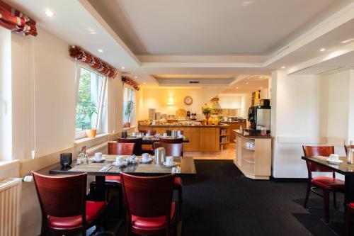 a restaurant with tables and chairs and a kitchen at Garner Hotel Bremen North by IHG in Bremen