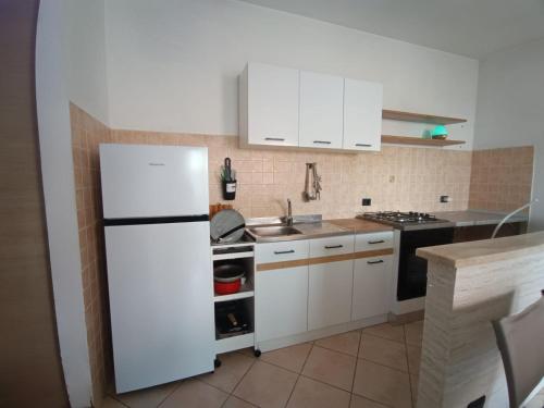 a kitchen with a white refrigerator and a sink at Guest House Riva Tognazzi Casa Vacanze in Torvaianica