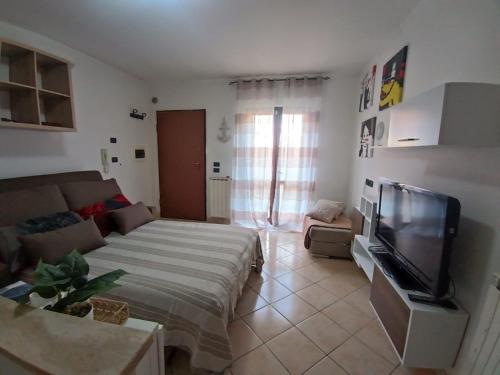 a living room with a bed and a flat screen tv at Guest House Riva Tognazzi Casa Vacanze in Torvaianica