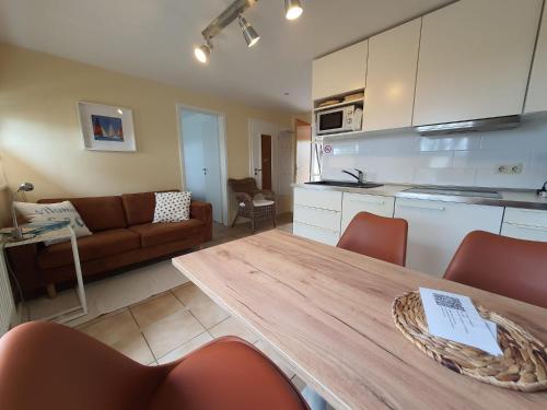 a kitchen and living room with a table and a couch at Haus Achtern Diek in erster Reihe am Meer in Fehmarn