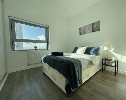 a white bedroom with a bed and a window at Bright & Spacious Flat In London in Croydon