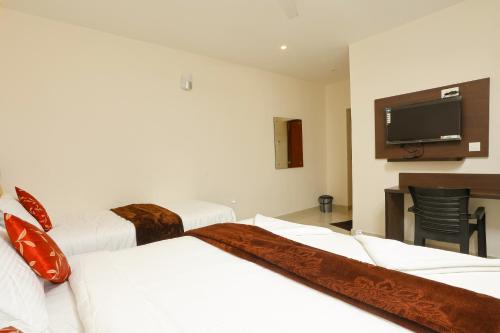 a hotel room with two beds and a flat screen tv at Rameswaram Harish Palace in Rāmeswaram